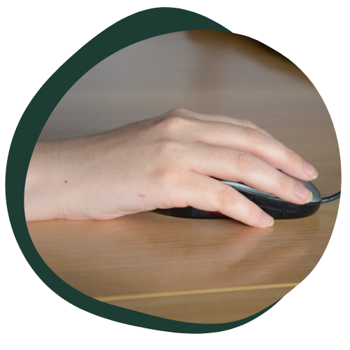 A close up image of a hand using a computer mouse at a desk. 