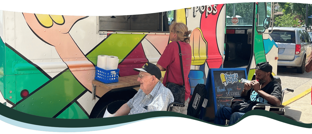 Three people, two of whom use wheelchairs, are ordering from a food truck